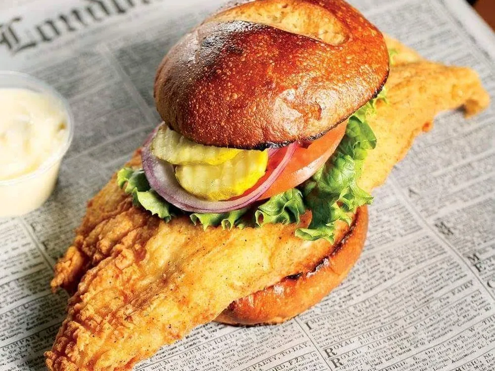 Caplinger's fried fish fillet sandwich on a toasted bun with lettuce, tomato, onion and pickles